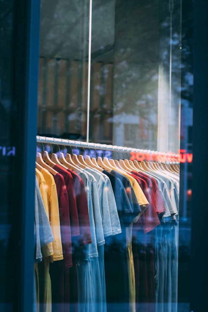 Colorful t-shirts hanging in a store window, showcasing a vibrant display.